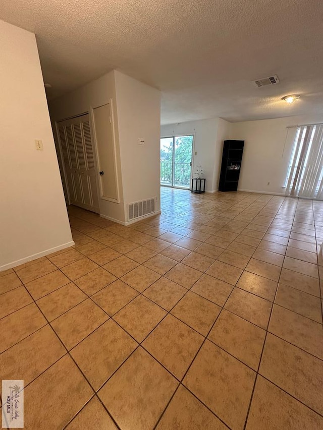 spare room featuring light tile patterned floors and a textured ceiling