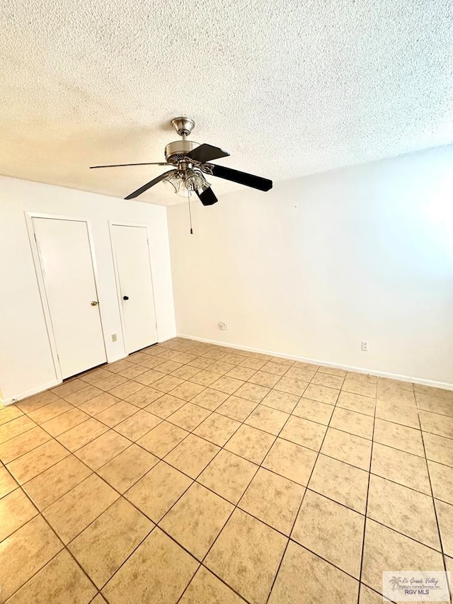 unfurnished room featuring ceiling fan, light tile patterned floors, and a textured ceiling