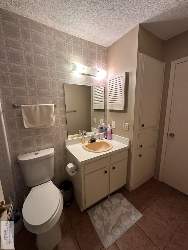 bathroom featuring tile patterned floors, vanity, a textured ceiling, and toilet