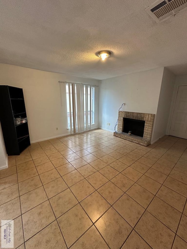 unfurnished living room featuring a fireplace, light tile patterned flooring, and a textured ceiling