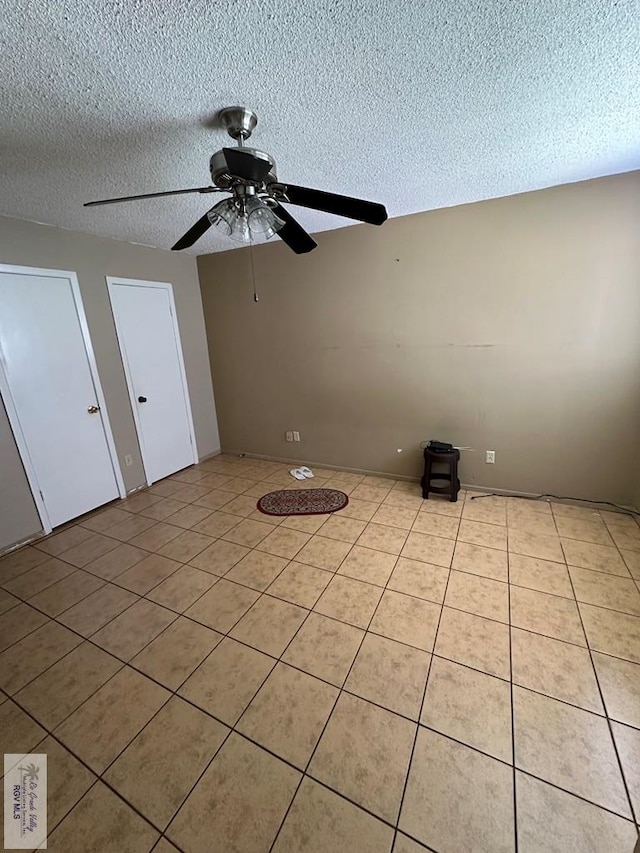 spare room with light tile patterned floors, a textured ceiling, and ceiling fan