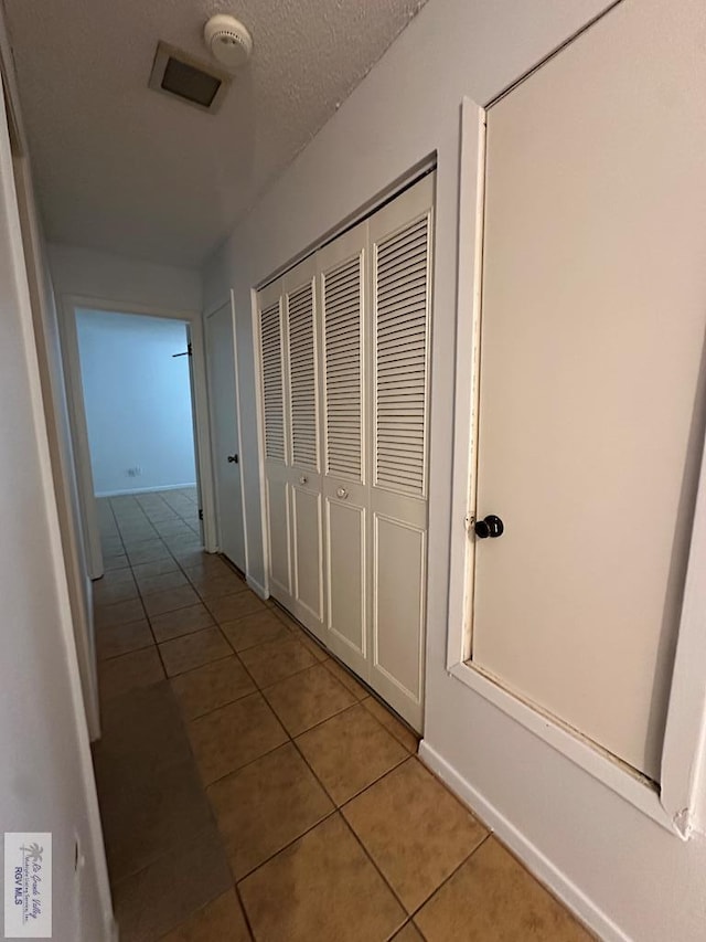 hallway with light tile patterned floors and a textured ceiling