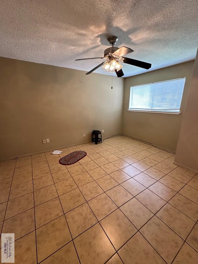 tiled empty room featuring a textured ceiling and ceiling fan