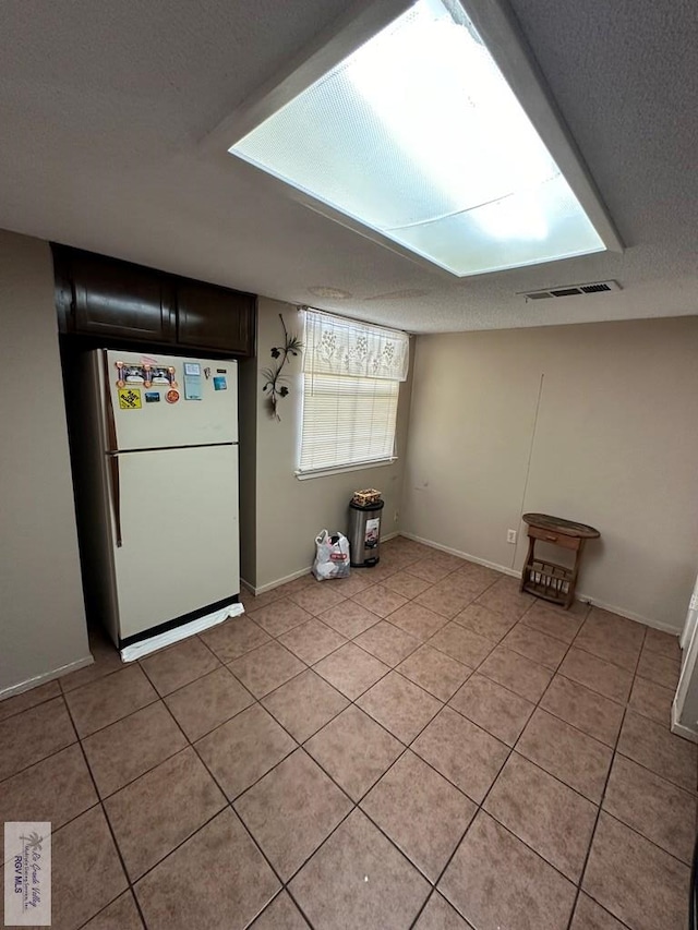 interior space featuring light tile patterned floors, white fridge, and a textured ceiling