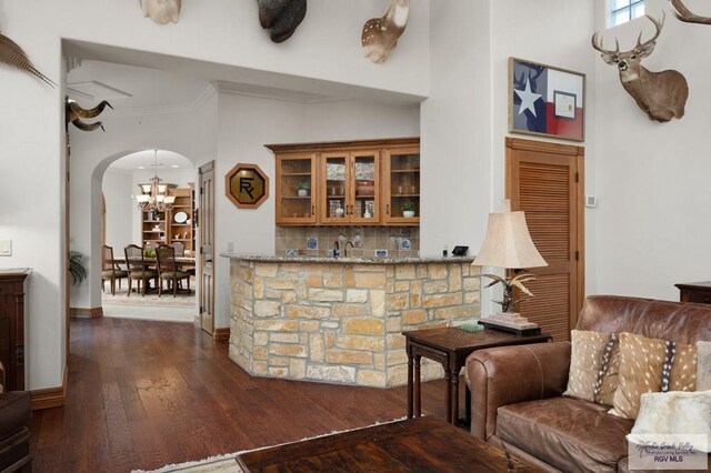 bar with light stone countertops, backsplash, dark hardwood / wood-style floors, and ornamental molding