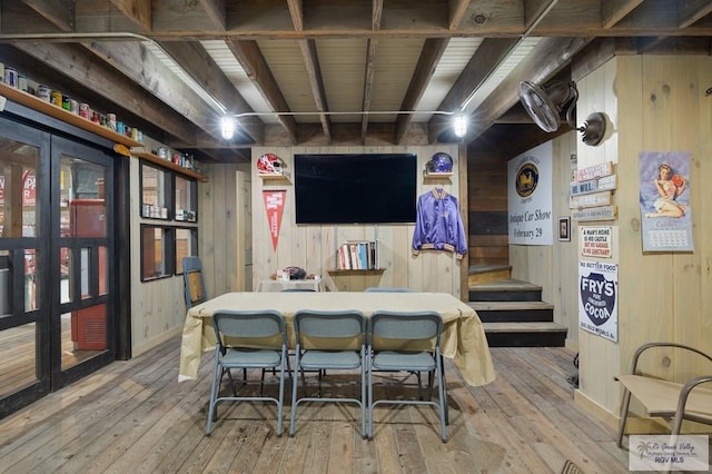 dining room with light wood-type flooring and wooden walls