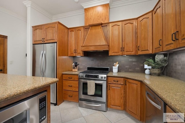 kitchen featuring crown molding, decorative backsplash, light stone countertops, custom range hood, and stainless steel appliances