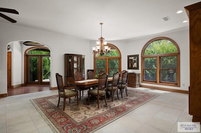 dining space with french doors, light tile patterned floors, ceiling fan with notable chandelier, and ornamental molding