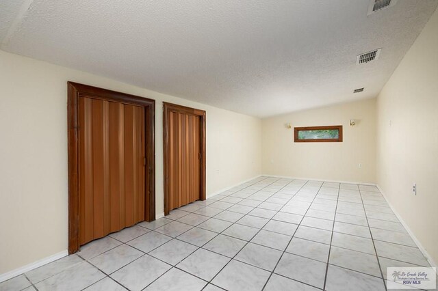 tiled spare room with vaulted ceiling and a textured ceiling