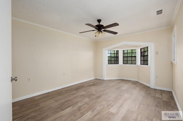 empty room with a textured ceiling, ceiling fan, light wood-type flooring, and ornamental molding