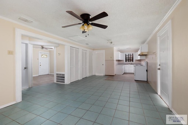 unfurnished living room with a textured ceiling, ceiling fan, light tile patterned floors, and crown molding