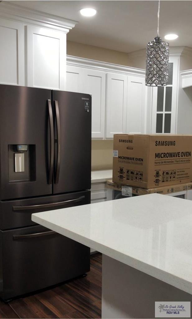 kitchen featuring white cabinets, hanging light fixtures, dark hardwood / wood-style flooring, fridge with ice dispenser, and a chandelier