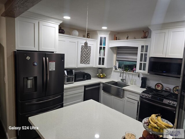 kitchen featuring black gas range, white cabinetry, and sink