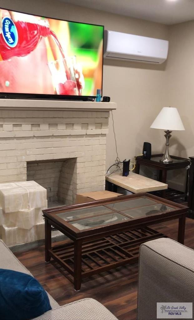 living room with dark hardwood / wood-style flooring, a wall unit AC, and a brick fireplace