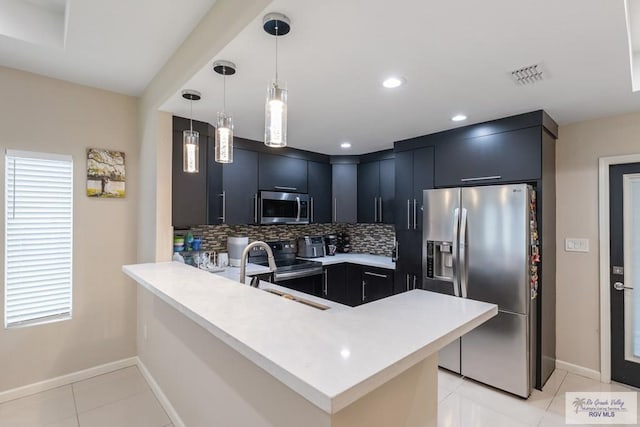 kitchen with sink, decorative light fixtures, kitchen peninsula, stainless steel appliances, and backsplash