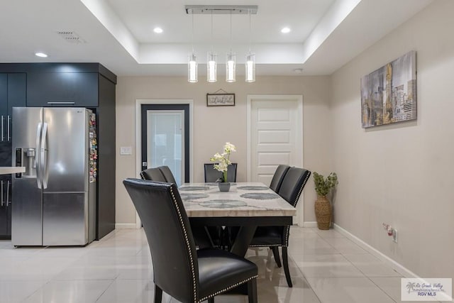 tiled dining area featuring a tray ceiling