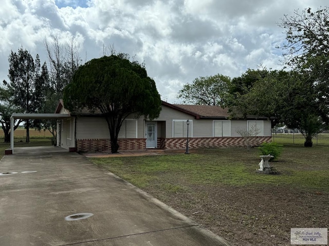 25631 N White Ranch Rd, La Feria, TX 78559 - view of front of house featuring brick siding, driveway, a front yard, and an attached carport