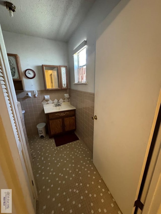 25631 N White Ranch Rd, La Feria, TX 78559 - bathroom featuring tile walls, vanity, a textured ceiling, and a wainscoted wall