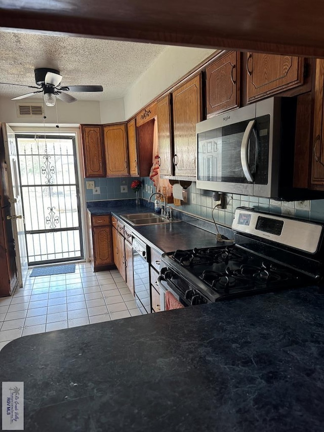 25631 N White Ranch Rd, La Feria, TX 78559 - kitchen with appliances with stainless steel finishes, decorative backsplash, light tile patterned flooring, a ceiling fan, and brown cabinetry