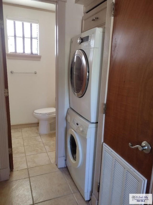 laundry area featuring stacked washing maching and dryer and light tile patterned flooring