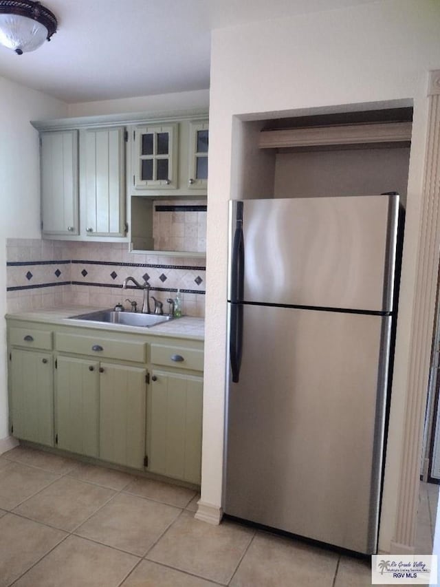 kitchen featuring stainless steel fridge, light tile patterned flooring, sink, and tasteful backsplash