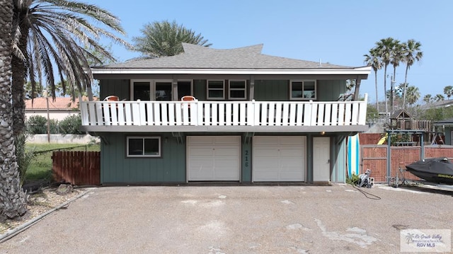 view of front of house featuring a garage, roof with shingles, fence, and driveway