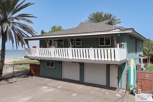 view of front of house with a garage, aphalt driveway, roof with shingles, a water view, and fence