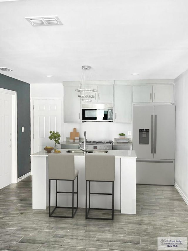 1105 W La Pointe Ave, Alton, TX 78573 - kitchen with stainless steel appliances, a kitchen bar, light countertops, a kitchen island with sink, and wood finished floors