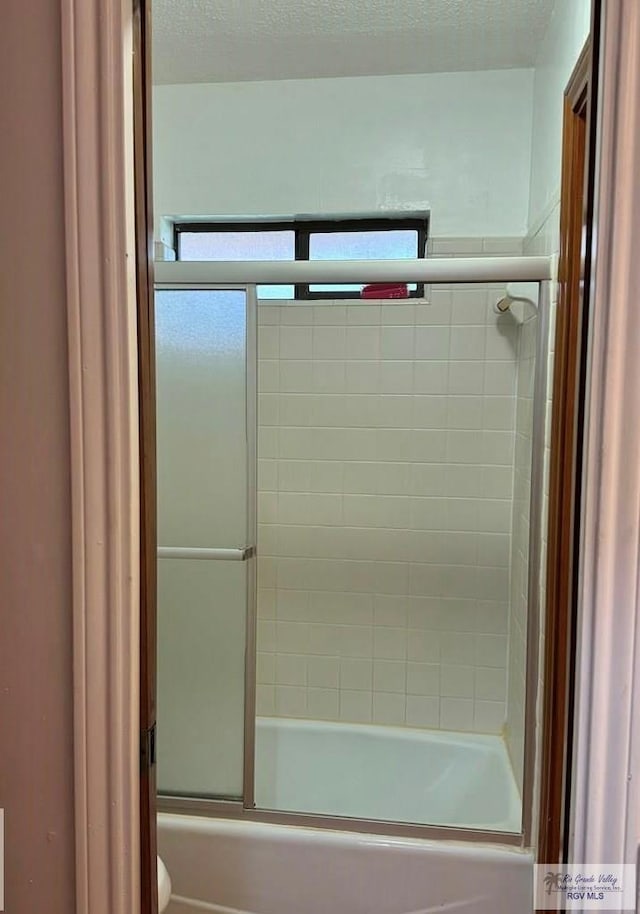 bathroom with shower / bath combination with glass door and toilet