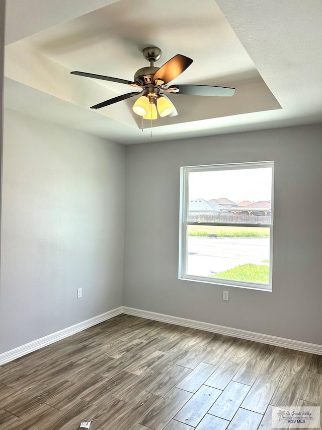 unfurnished room featuring wood-type flooring, a tray ceiling, and ceiling fan