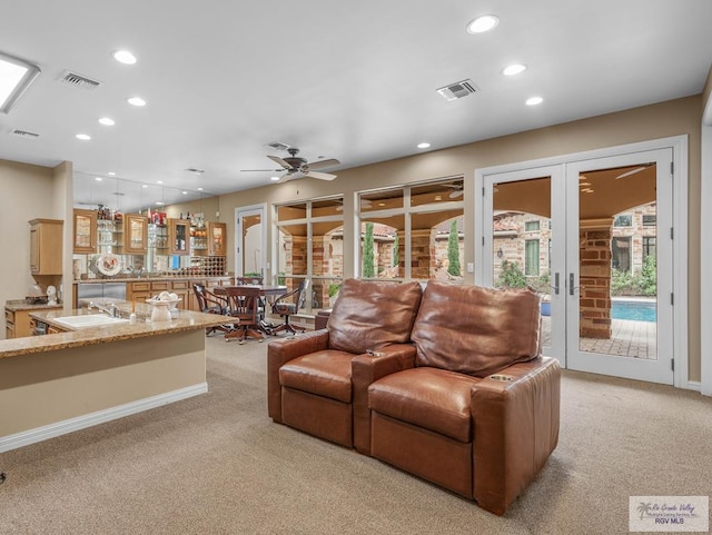 carpeted living room featuring french doors, ceiling fan, and sink