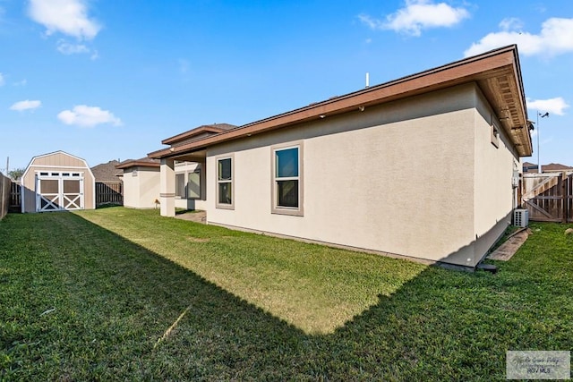 rear view of house featuring a yard, central AC, and a storage unit