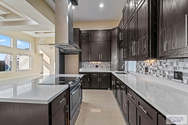 kitchen with light stone countertops, sink, island range hood, and stainless steel range with electric stovetop