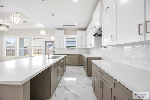 5359 Sidekick Ave, Brownsville, TX 78526 - kitchen with decorative backsplash, a kitchen island with sink, recessed lighting, light stone counters, and under cabinet range hood