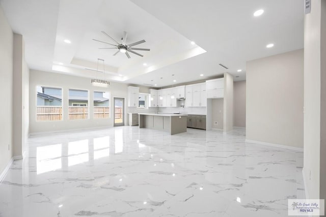 5359 Sidekick Ave, Brownsville, TX 78526 - unfurnished living room with a tray ceiling, ceiling fan, recessed lighting, and light marble finish flooring