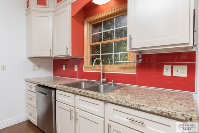 701 S Parker Rd, La Feria, TX 78559 - kitchen featuring white cabinetry, stainless steel dishwasher, a sink, baseboards, and backsplash