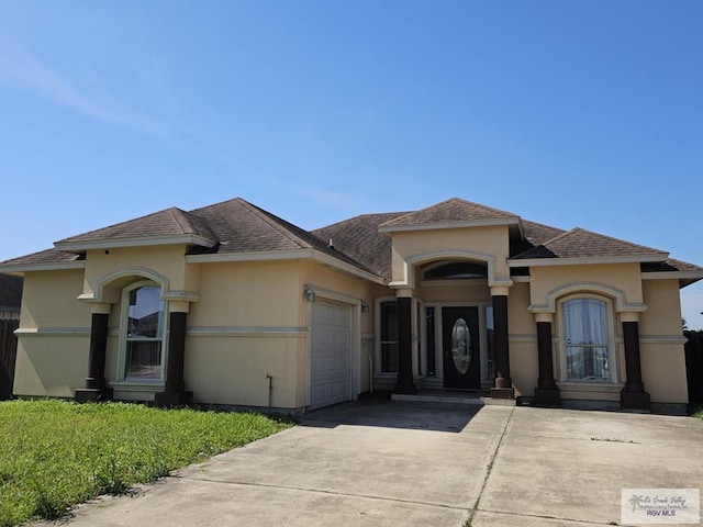 2884 Gibraltar St, Brownsville, TX 78520 - mediterranean / spanish house with an attached garage, concrete driveway, stucco siding, and roof with shingles