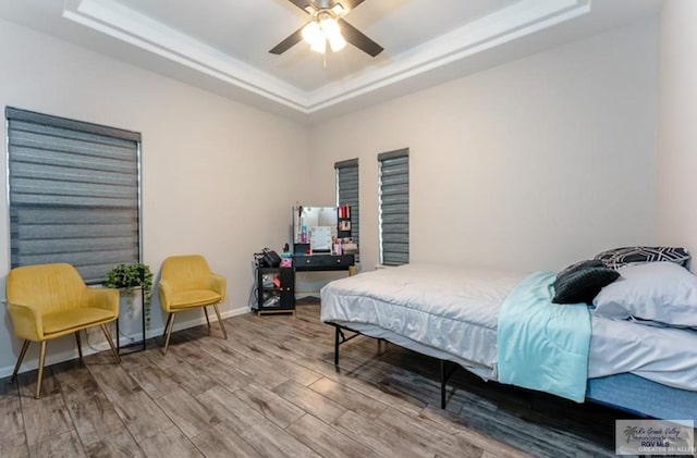 bedroom with a tray ceiling, ceiling fan, and hardwood / wood-style flooring