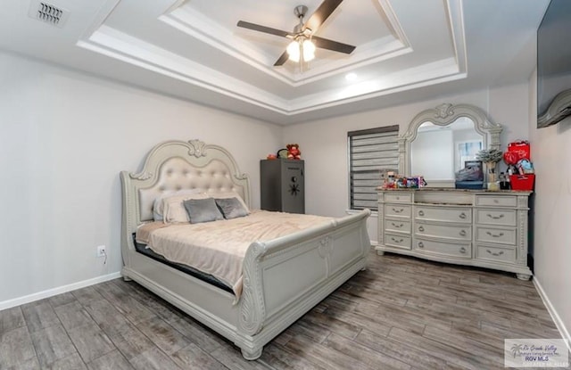 bedroom with a raised ceiling, ceiling fan, and hardwood / wood-style floors