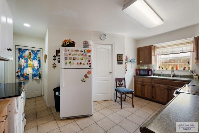 kitchen featuring black appliances, light tile patterned floors, and sink