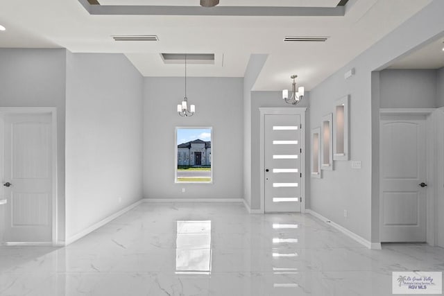 foyer featuring a tray ceiling and a chandelier