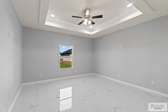 spare room featuring ceiling fan and a tray ceiling