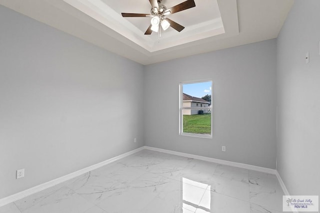 spare room with ceiling fan and a tray ceiling