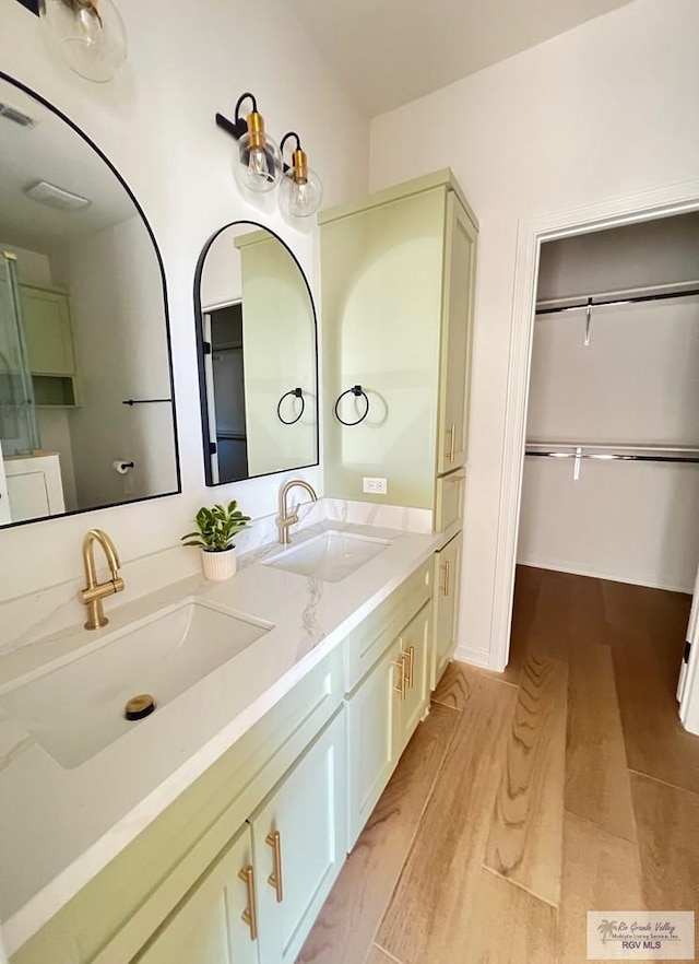 bathroom with double vanity, wood finished floors, a sink, and visible vents