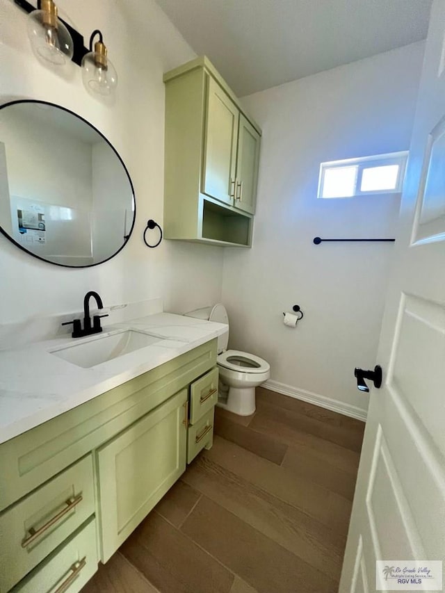 bathroom with vanity, wood finished floors, toilet, and baseboards