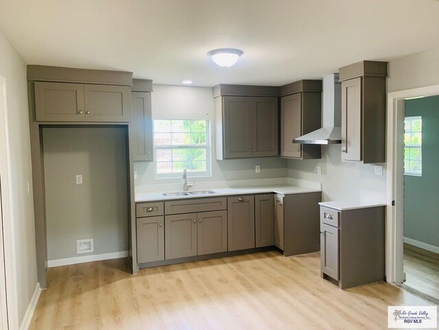 1218 S 16th St, Harlingen, TX 78550 - kitchen featuring wall chimney range hood, light wood-type flooring, gray cabinets, and light countertops