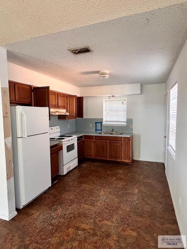 kitchen with a healthy amount of sunlight, white appliances, and a textured ceiling