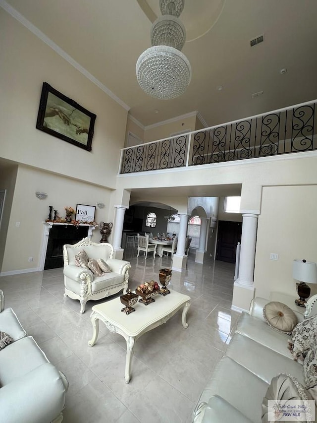 living room featuring a chandelier, a high ceiling, ornate columns, and crown molding