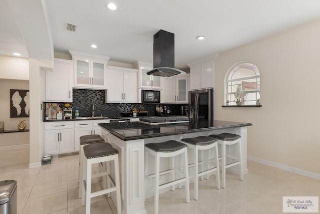 kitchen featuring island exhaust hood, stainless steel fridge, backsplash, a breakfast bar, and a kitchen island