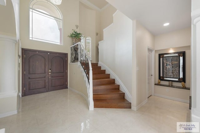 entryway with light tile patterned floors and a towering ceiling